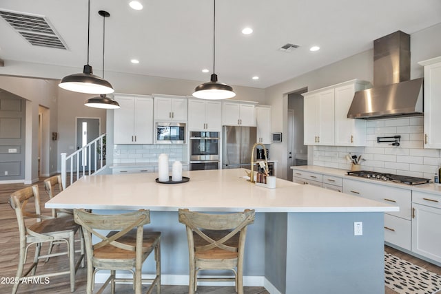 826 E Buist Ave, Phoenix, AZ 85042 - kitchen featuring wall chimney exhaust hood, stainless steel appliances, backsplash, an island with sink, and a sink