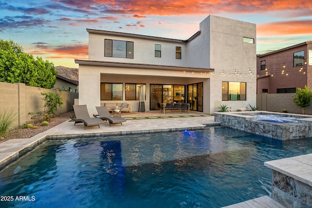 826 E Buist Ave, Phoenix, AZ 85042 - back of property at dusk with a fenced backyard, a patio, stucco siding, and a pool with connected hot tub