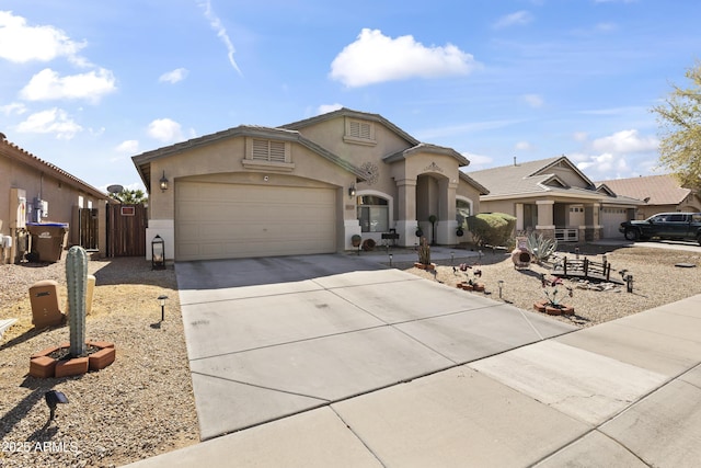 mediterranean / spanish home featuring stucco siding, concrete driveway, a garage, and fence