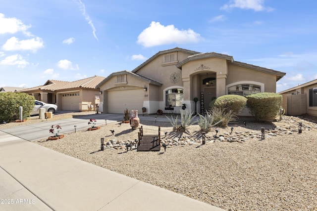 mediterranean / spanish-style house with an attached garage, driveway, and stucco siding