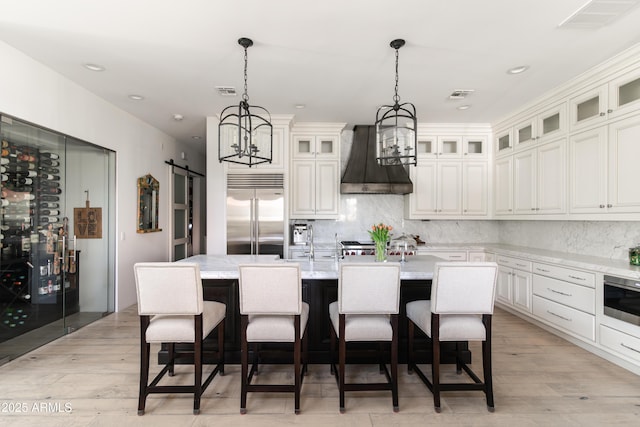 3511 N 39th Pl, Phoenix, AZ 85018 - kitchen featuring stainless steel built in fridge, custom exhaust hood, a barn door, a center island with sink, and a chandelier
