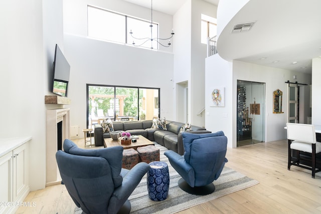 3511 N 39th Pl, Phoenix, AZ 85018 - living room featuring a chandelier, a towering ceiling, light wood-style floors, a high end fireplace, and a barn door