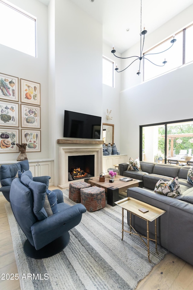 3511 N 39th Pl, Phoenix, AZ 85018 - living room featuring a high ceiling, a chandelier, wood finished floors, and a lit fireplace