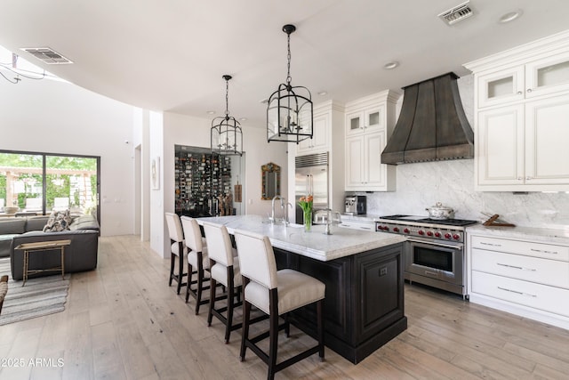 3511 N 39th Pl, Phoenix, AZ 85018 - kitchen featuring premium appliances, premium range hood, a breakfast bar area, a chandelier, and light wood-style floors