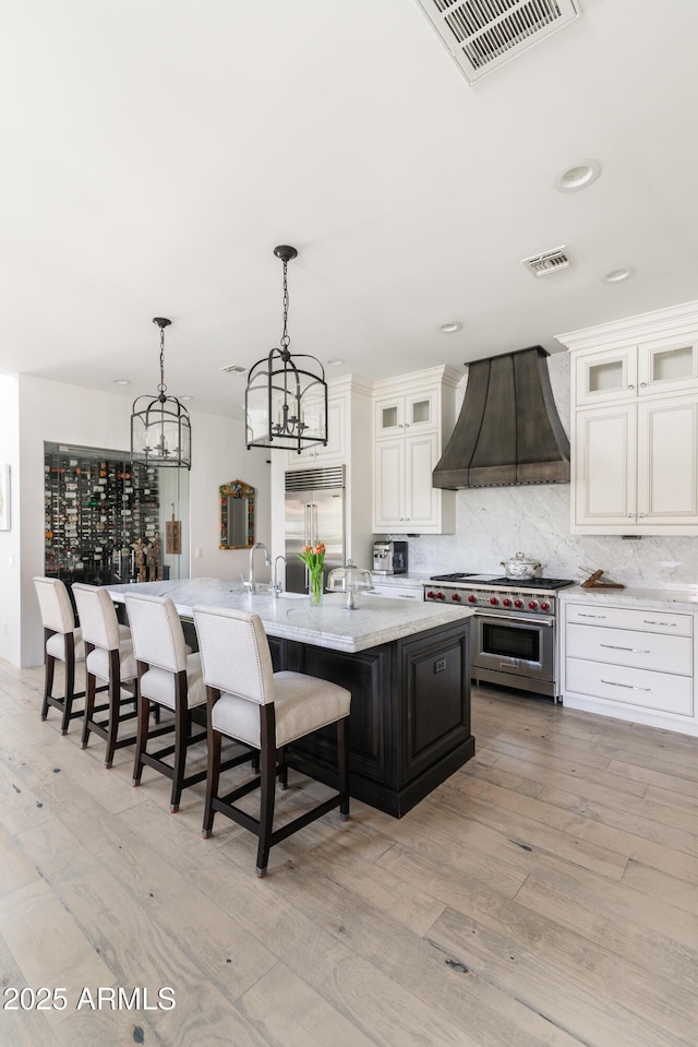 3511 N 39th Pl, Phoenix, AZ 85018 - kitchen with premium range hood, high quality appliances, a kitchen bar, a center island with sink, and backsplash