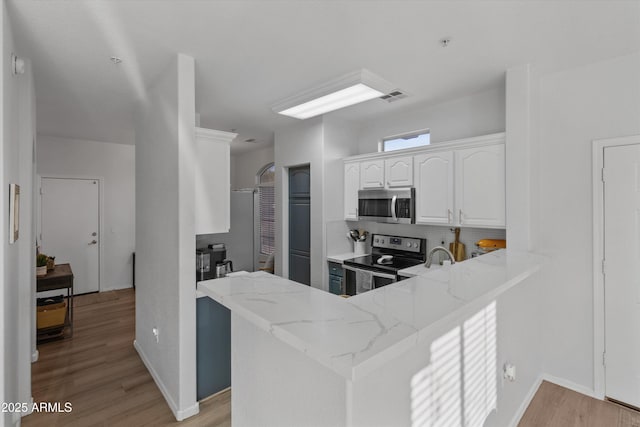 470 N 168th Ln, Goodyear, AZ 85338 - kitchen featuring light stone counters, visible vents, white cabinets, appliances with stainless steel finishes, and light wood-type flooring