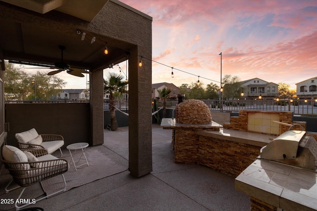 470 N 168th Ln, Goodyear, AZ 85338 - patio terrace at dusk with area for grilling, a ceiling fan, and fence
