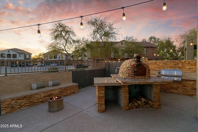 470 N 168th Ln, Goodyear, AZ 85338 - patio terrace at dusk with an outdoor kitchen, a grill, and fence