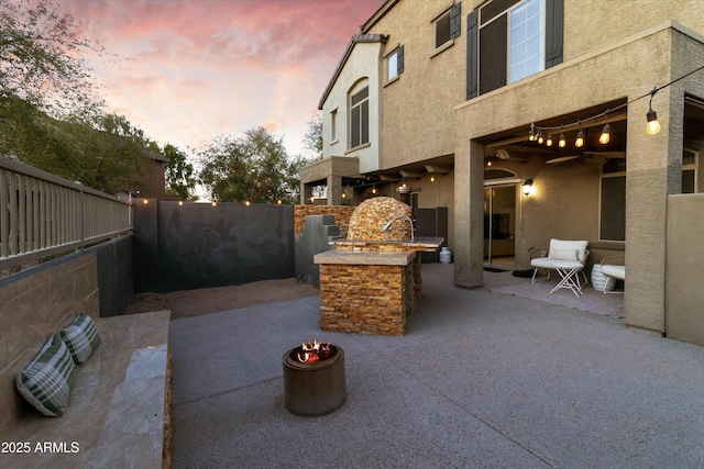 470 N 168th Ln, Goodyear, AZ 85338 - patio terrace at dusk with an outdoor kitchen, a fenced backyard, and a ceiling fan
