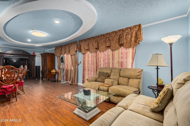 living area featuring a tray ceiling, crown molding, a textured ceiling, and wood finished floors