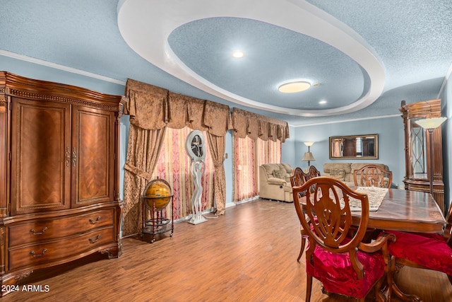 dining room with a raised ceiling, a textured ceiling, and wood finished floors