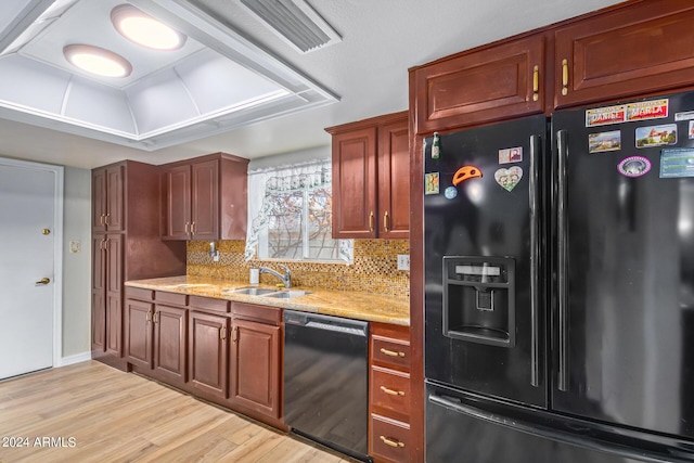 kitchen featuring light wood finished floors, backsplash, a sink, light stone countertops, and black appliances