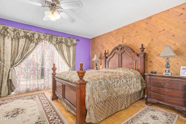 bedroom featuring a textured ceiling, wood walls, and a ceiling fan