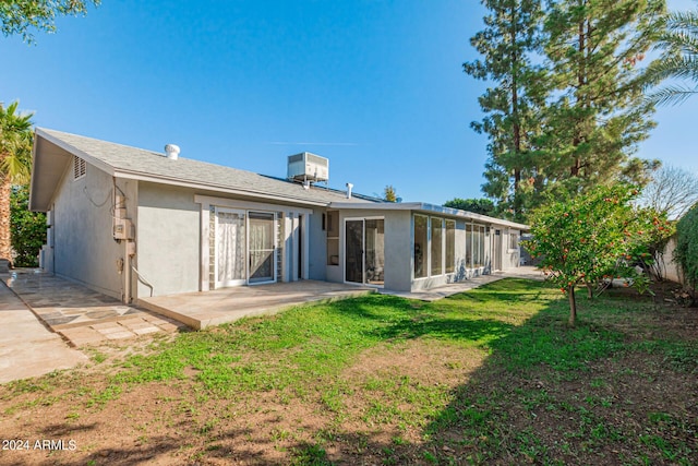 back of property with a patio, central AC, a sunroom, a yard, and stucco siding