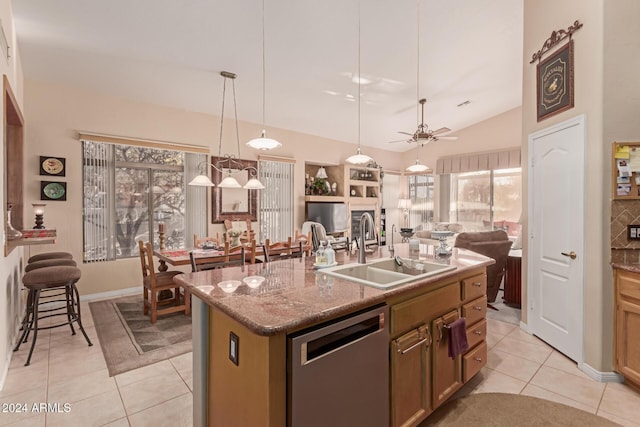 kitchen with ceiling fan, dishwasher, sink, light tile patterned flooring, and a kitchen island with sink