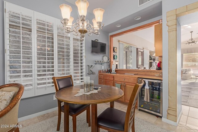 dining space featuring light tile patterned floors, beverage cooler, and an inviting chandelier