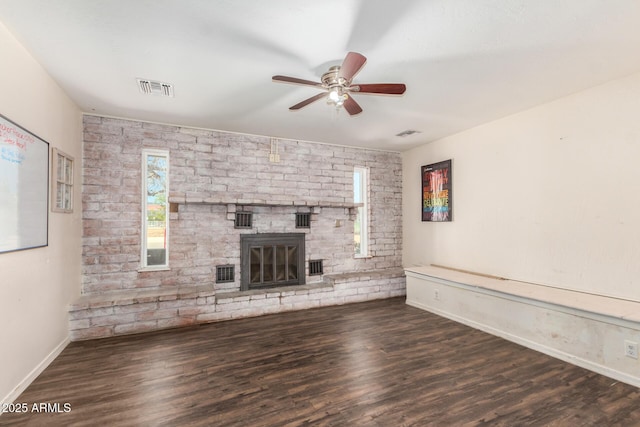 unfurnished living room featuring a ceiling fan, a fireplace, visible vents, and dark wood-type flooring