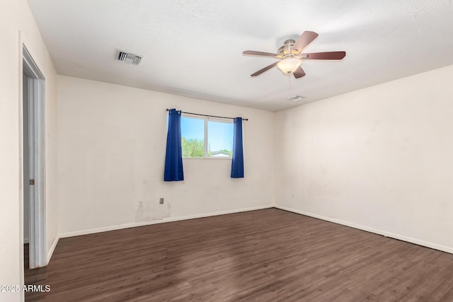 spare room with dark wood-style floors, visible vents, and ceiling fan