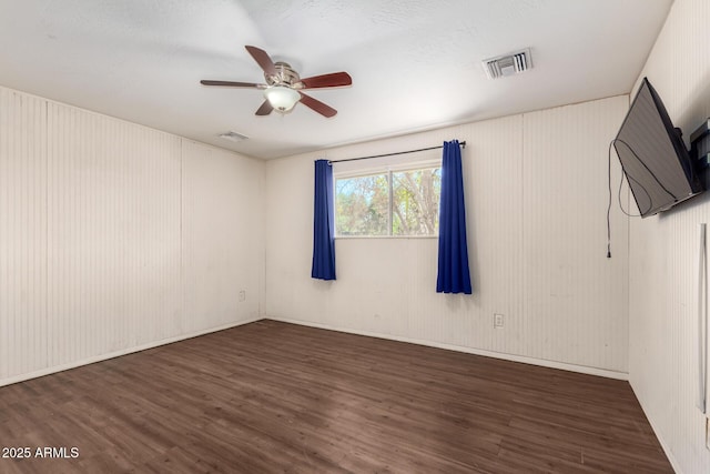 unfurnished room featuring dark wood-type flooring, visible vents, and a ceiling fan