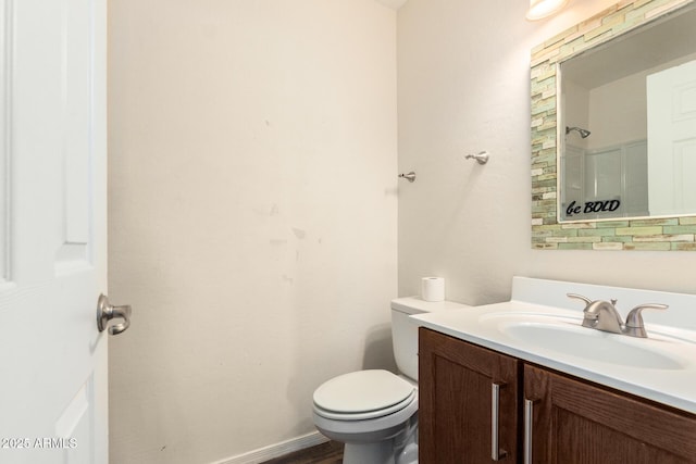 bathroom featuring toilet, baseboards, a shower, and vanity