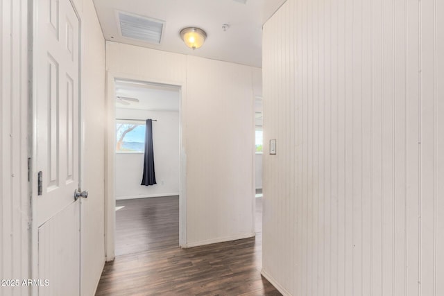 hallway with dark wood-style floors, baseboards, and visible vents