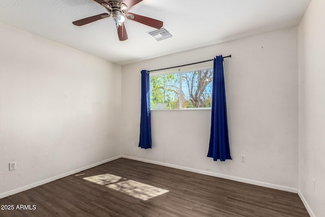 spare room featuring dark wood-style floors, visible vents, and baseboards