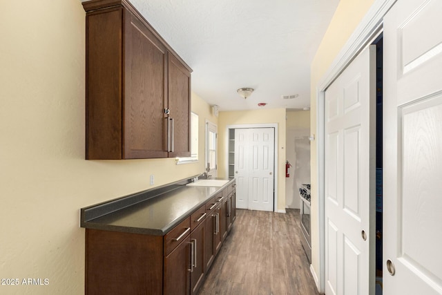 hallway featuring dark wood-style flooring, visible vents, and a sink