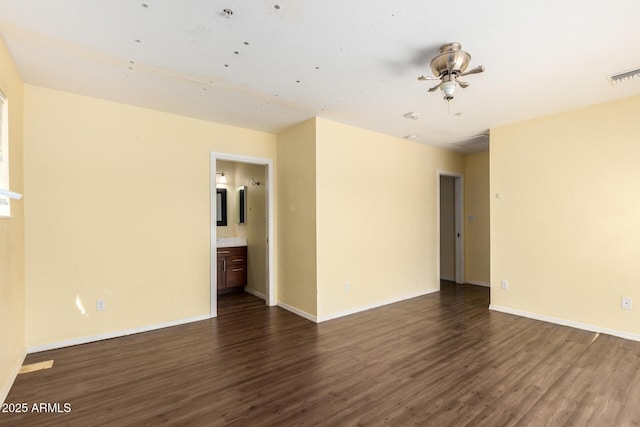 empty room with dark wood-style floors, baseboards, and visible vents