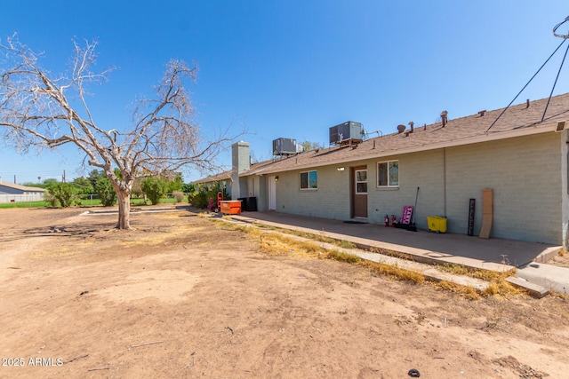 back of house featuring brick siding, cooling unit, and a patio