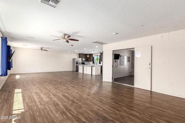 unfurnished living room featuring dark wood-style flooring, visible vents, and ceiling fan