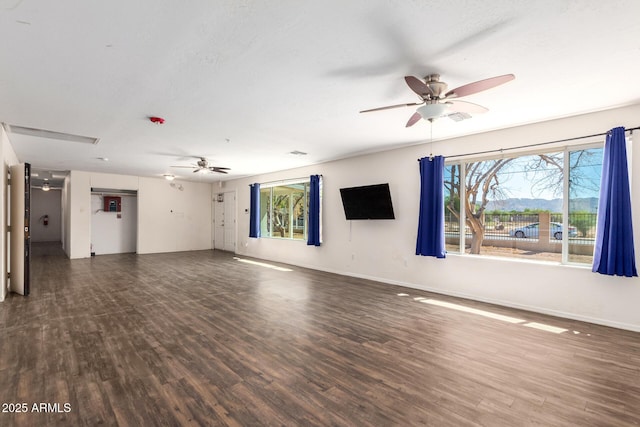 unfurnished living room with ceiling fan, dark wood-type flooring, a textured ceiling, and baseboards