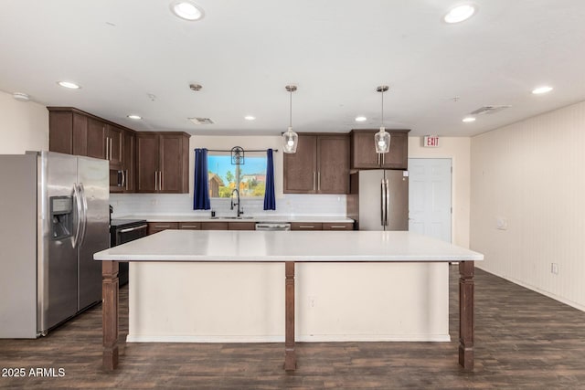 kitchen featuring pendant lighting, stainless steel appliances, light countertops, and a center island