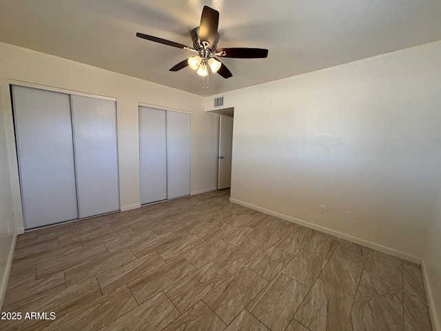 unfurnished bedroom with visible vents, multiple closets, baseboards, and ceiling fan