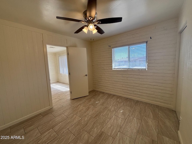 spare room featuring brick wall and ceiling fan