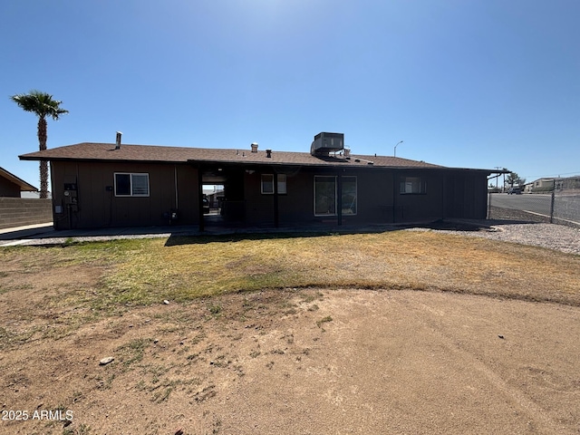 rear view of house with fence, board and batten siding, and central AC