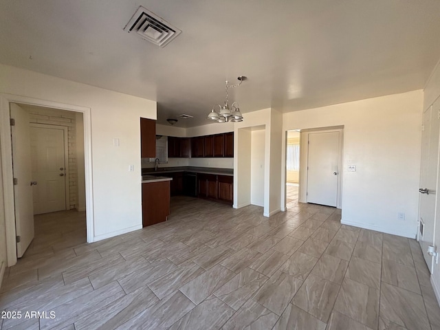 kitchen with visible vents, decorative light fixtures, open floor plan, dark brown cabinetry, and a notable chandelier