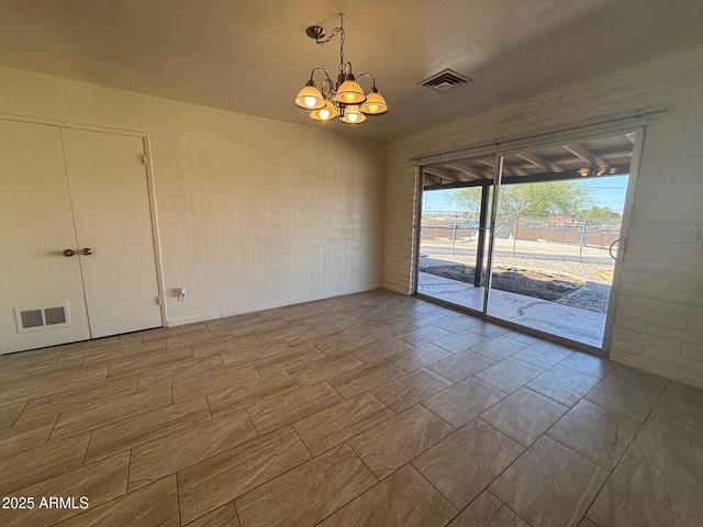 spare room featuring a chandelier and visible vents