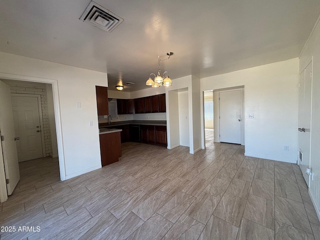 kitchen with dark brown cabinets, visible vents, an inviting chandelier, and open floor plan