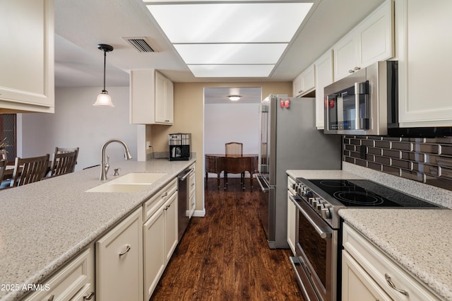 kitchen featuring appliances with stainless steel finishes, a sink, dark wood-style flooring, white cabinetry, and decorative backsplash