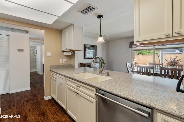 kitchen with a sink, dishwasher, dark wood-style flooring, light stone counters, and hanging light fixtures
