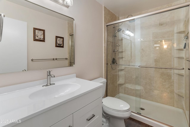 full bathroom featuring a stall shower, toilet, and vanity