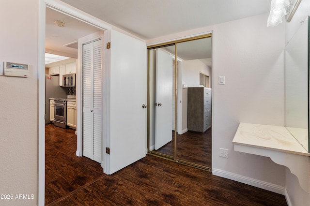 corridor featuring dark wood-style floors and baseboards