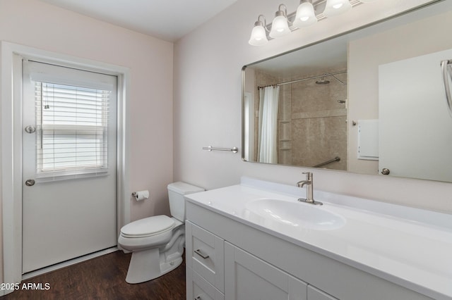 bathroom featuring wood finished floors, toilet, vanity, and curtained shower