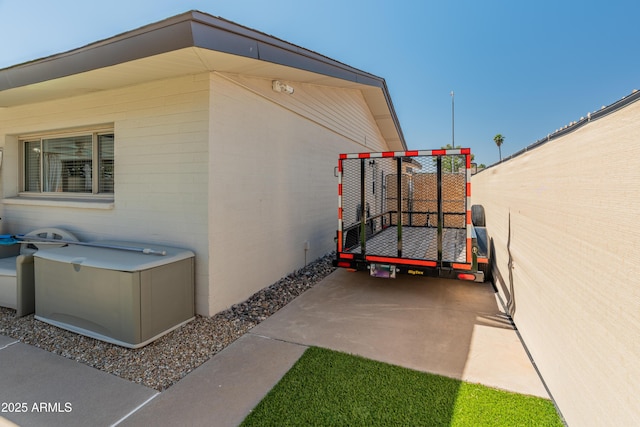 view of side of home with fence, concrete block siding, and a patio area