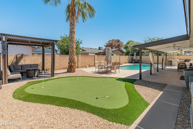 fenced backyard featuring an area to practice putting, outdoor lounge area, a patio, a ceiling fan, and a pergola
