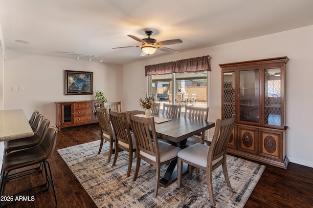 dining space featuring dark wood-style floors, a ceiling fan, track lighting, and baseboards
