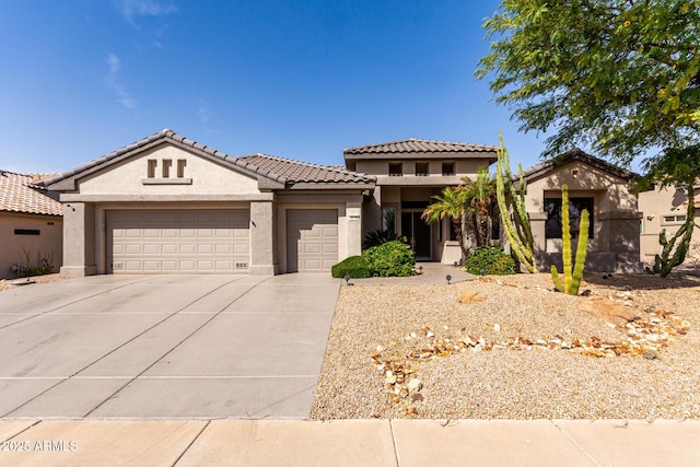 view of front of house featuring a garage, concrete driveway, a tiled roof, and stucco siding