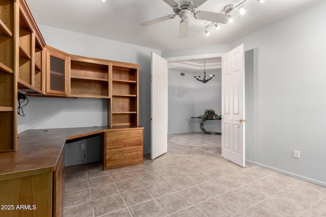 unfurnished office featuring light tile patterned floors, baseboards, a ceiling fan, and built in study area