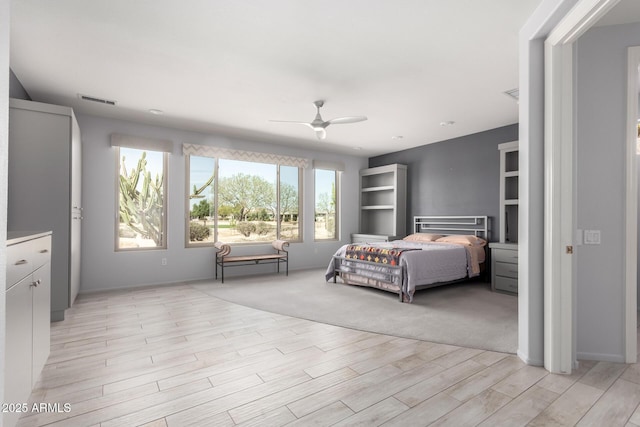 bedroom featuring light wood-style flooring, visible vents, and a ceiling fan