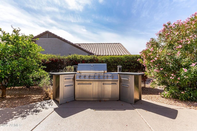 view of patio featuring exterior kitchen and a grill